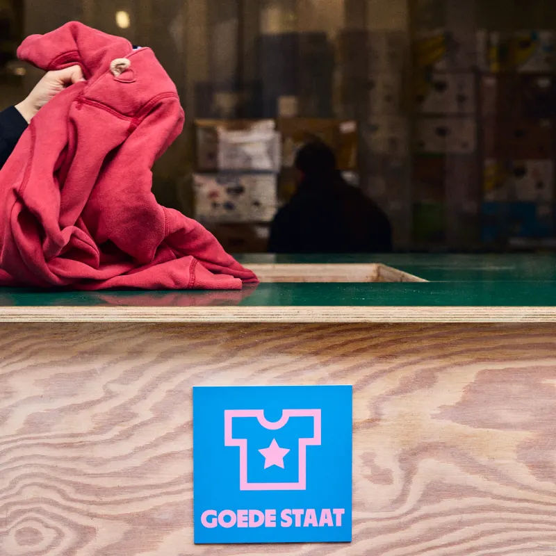 Een rode trui gaat in de bak voor textiel in goede staat.