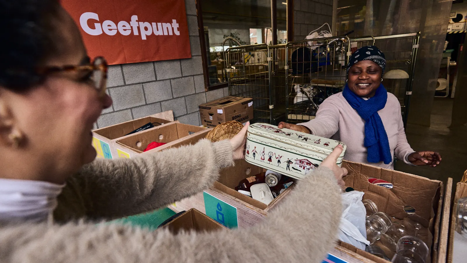 Aan het geefpunt geeft iemand een doos met spullen over de balie.