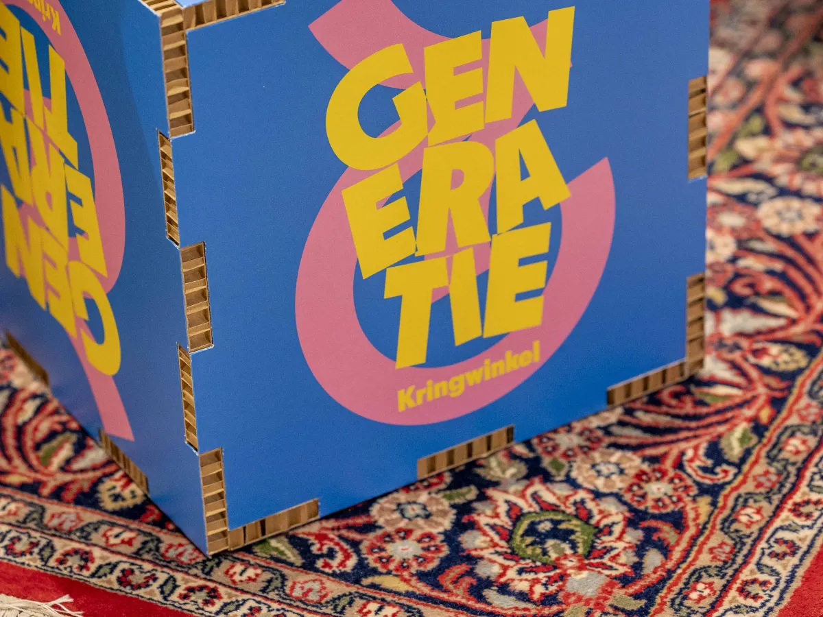 De kubus met het logo van Generatie Kringwinkel op een Perzisch tapijt in de Kringwinkel.